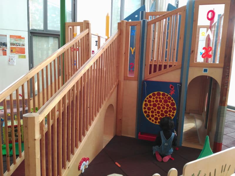 Zona de juegos interior en el restaurante - Cantina de la Universidad de Bremen - En la zona de juego hay bloques de construcción, una pequeña construcción con rampas y un tobogán, y distintos juegos sensoriales.