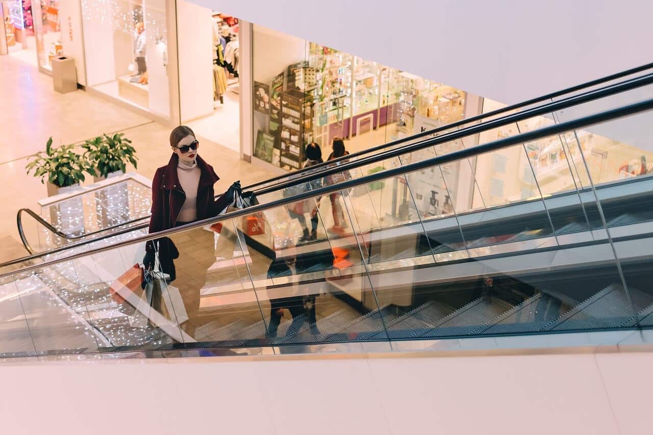 Centros comerciales en Bremen - Imagen ilustrativa mujer de compras subiendo en una escalera mecánica en un centro comercial